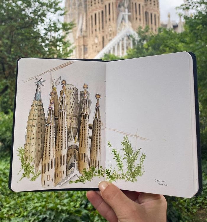 Sketchbook con la Sagrada Familia en acuarela, sostenido frente a las torres de la basílica